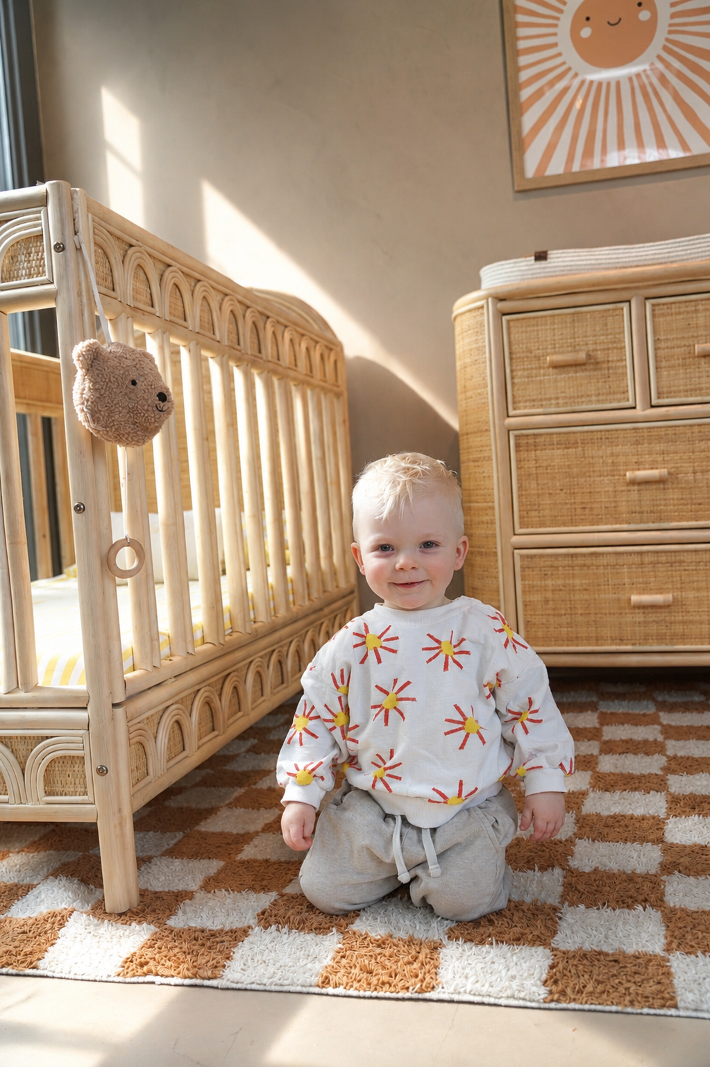 Rotan babybed met peuter en bijpassende rotan commode in een warme, natuurlijke kinderkamer