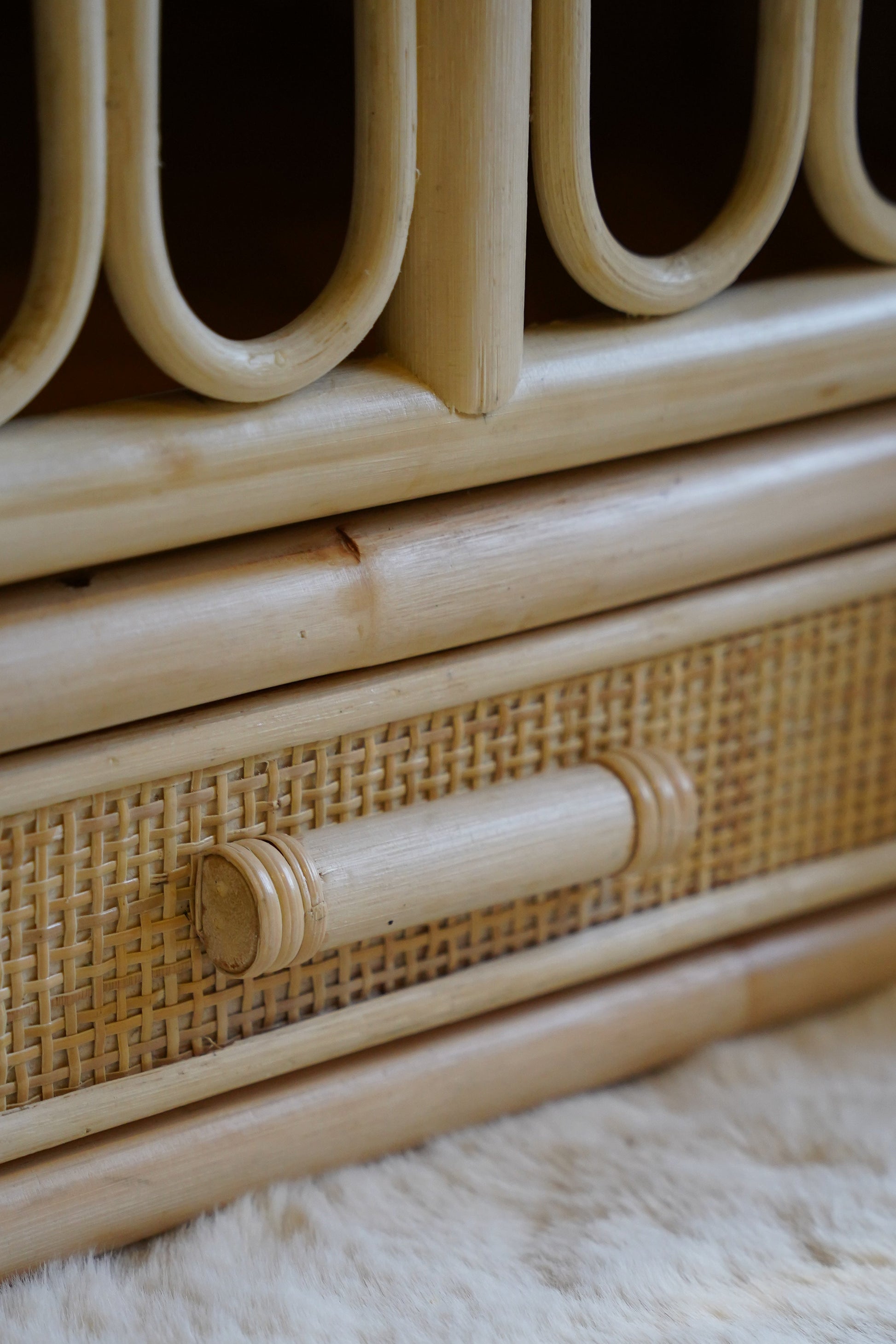 Detail van een naturel rotan babybed met geïntegreerde opberglade en handgevlochten afwerking
