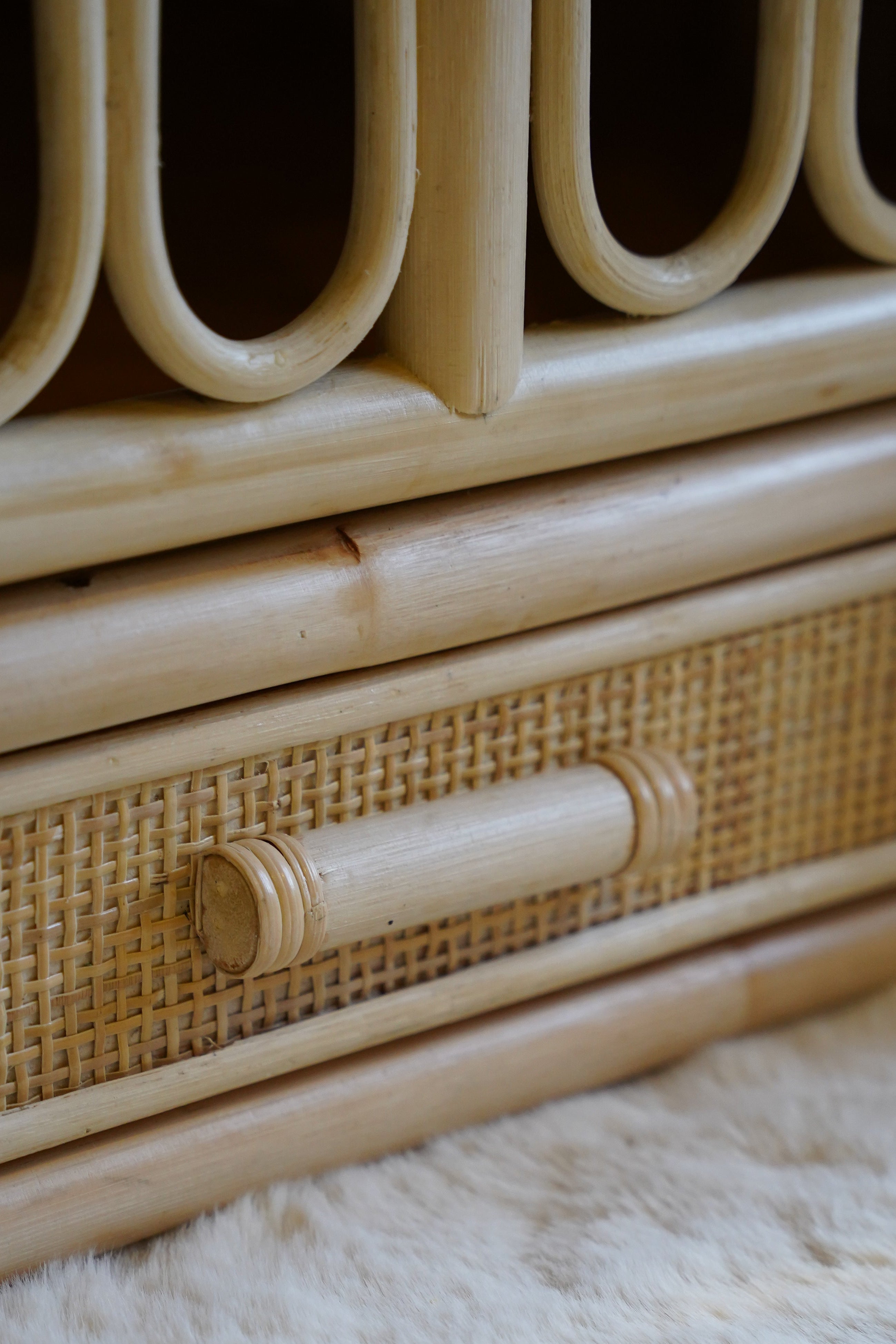 Detail van een naturel rotan babybed met geïntegreerde opberglade en handgevlochten afwerking