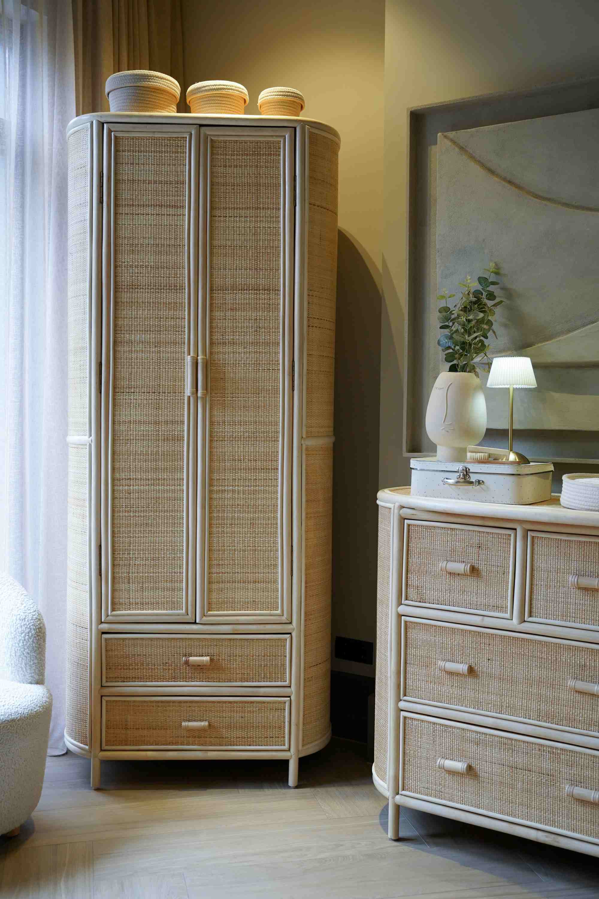 Rotan kledingkast en commode in een babykamer interieur met beige tinten.