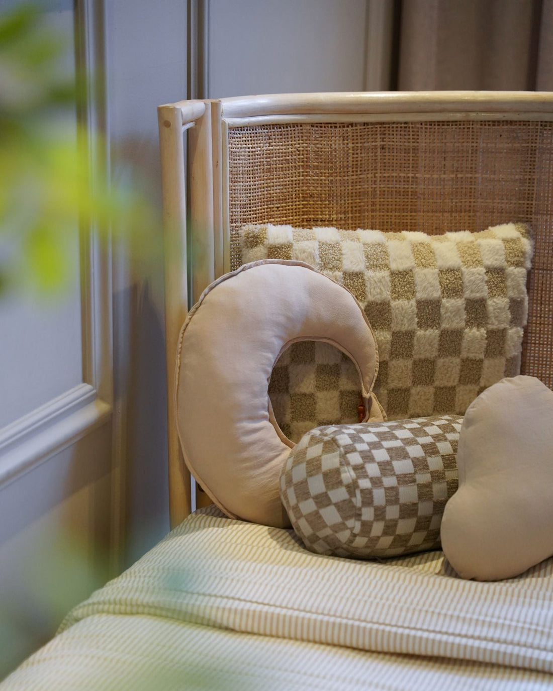 Detail van een naturel rotan kinderbed met handgevlochten hoofdbord en zachte sierkussens