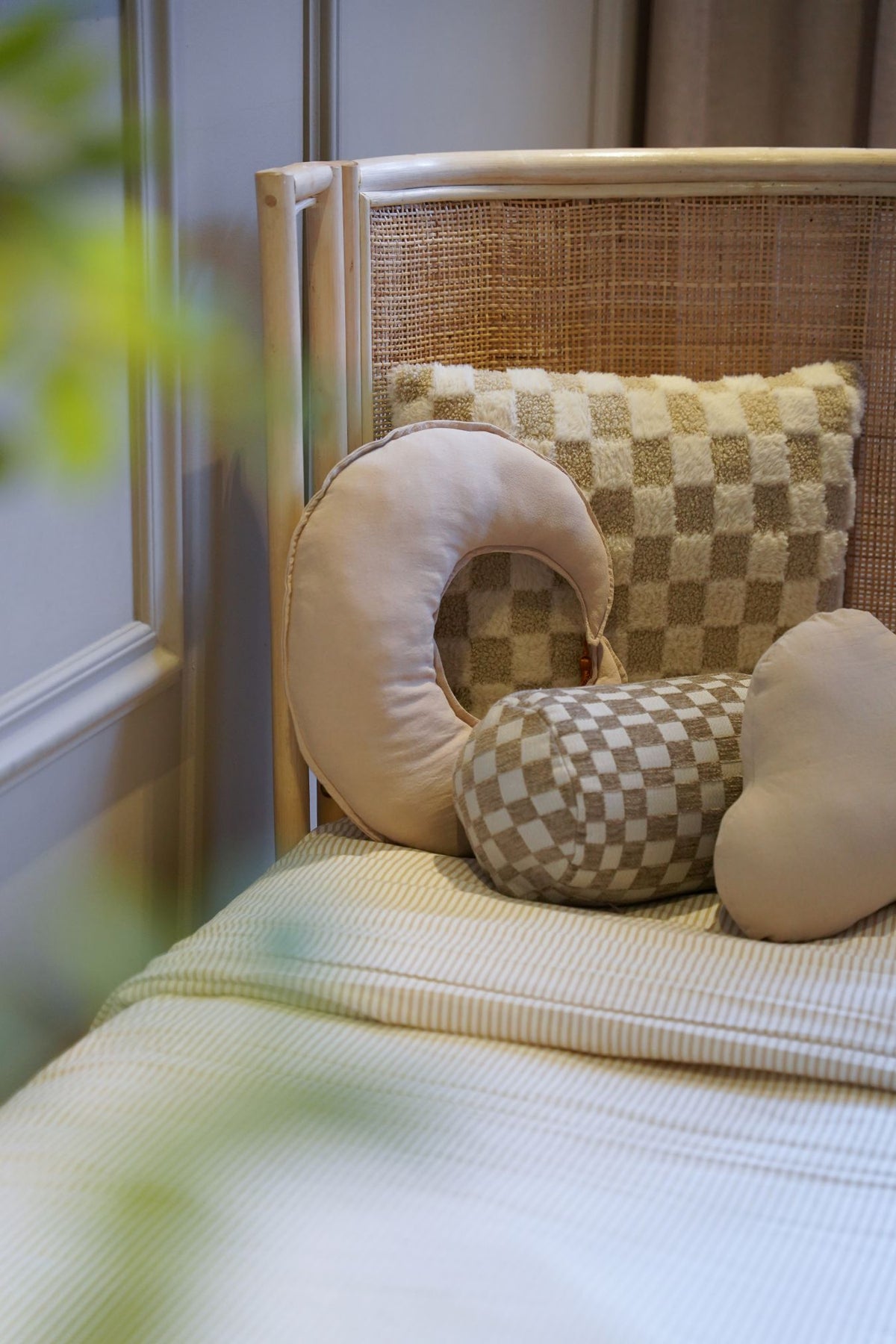 Detail van een rotan meegroeibed met handgevlochten hoofdbord, zachte knuffels en een geborgen slaapomgeving