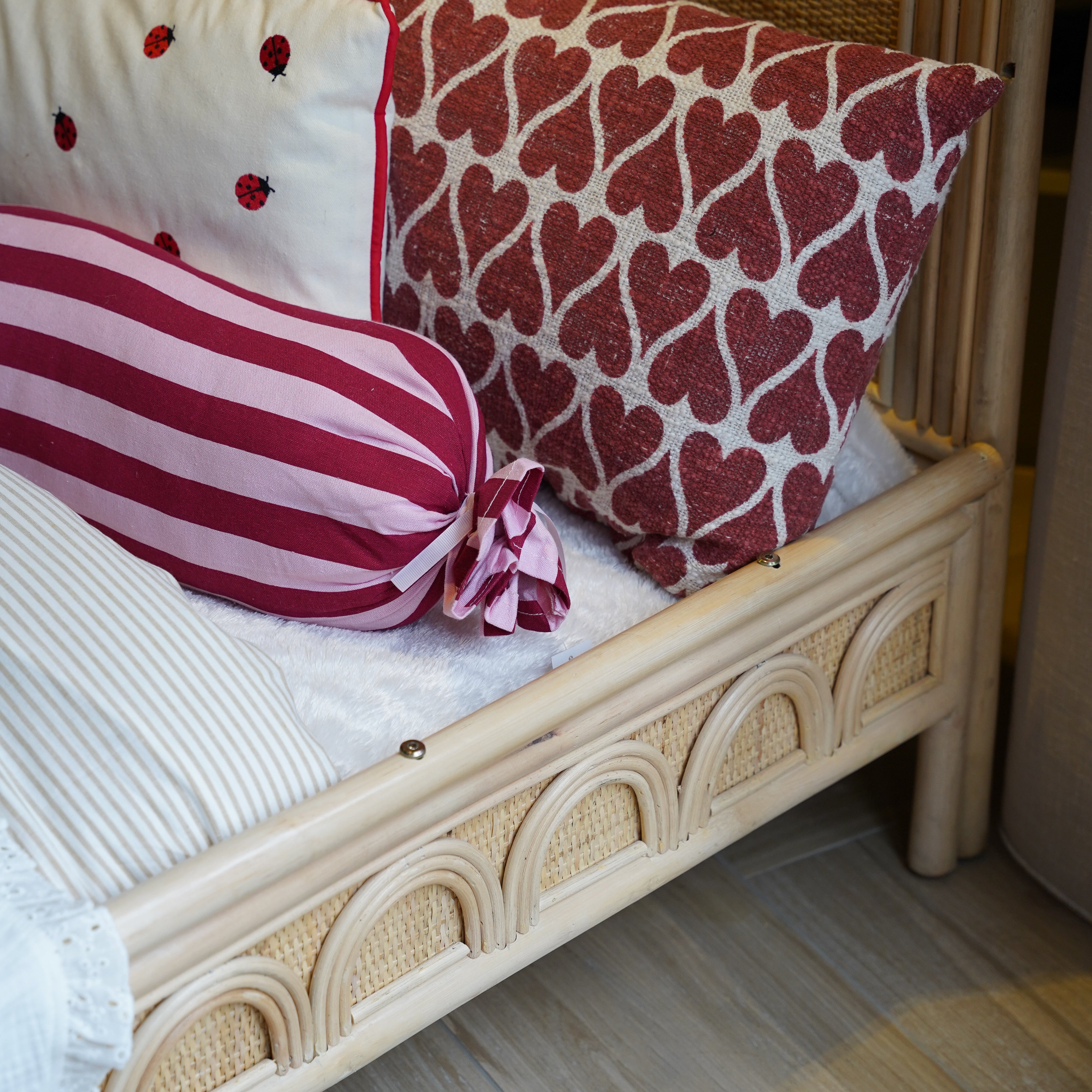 Detail van een naturel rotan kinderbed met handgevlochten afwerking en afgerond zijpaneel